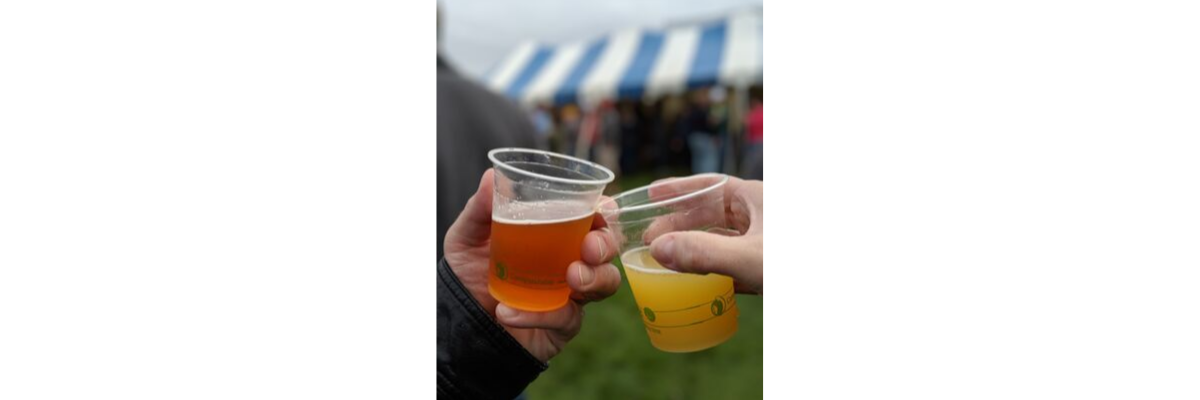 Two plastic beer cups clinking with a tent in the background.